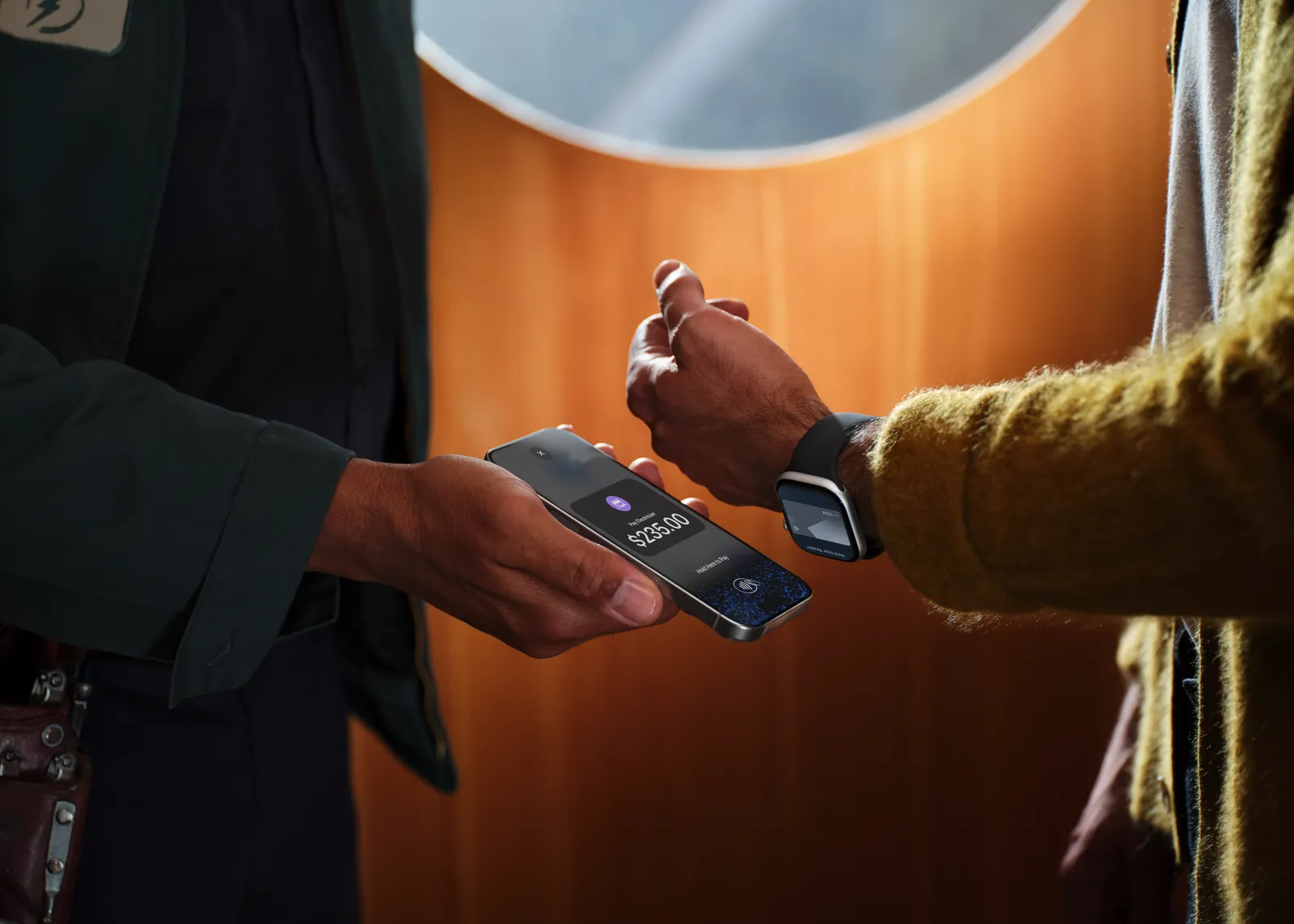 A client pays an electrician with Apple Watch held near the electrician's iPhone
